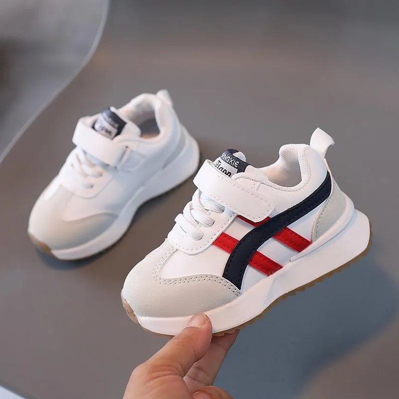 Children's white synthetic leather sneaker with Velcro strap on a rubber sole.