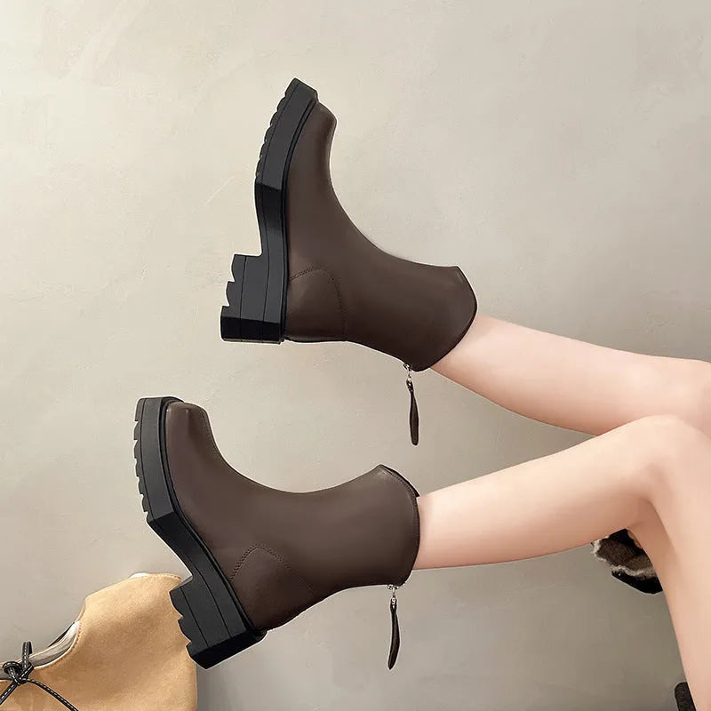 Black platform Martin ankle boots with a square toe, chunky heel, and back zipper on a woman's feet.