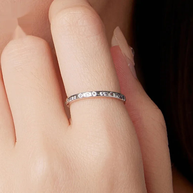 Close-up of a women's oxidised black silver alloy ring with an etched 'I love you' moss password design on a simple band.