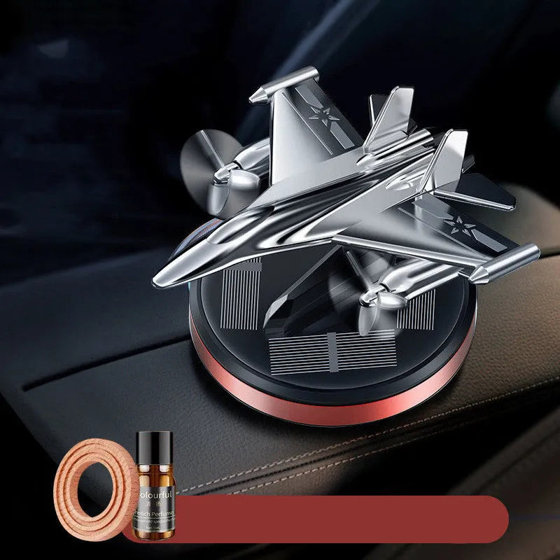 Solar powered rotating silver fighter jet perfume ornament with aluminium alloy base on a car dashboard