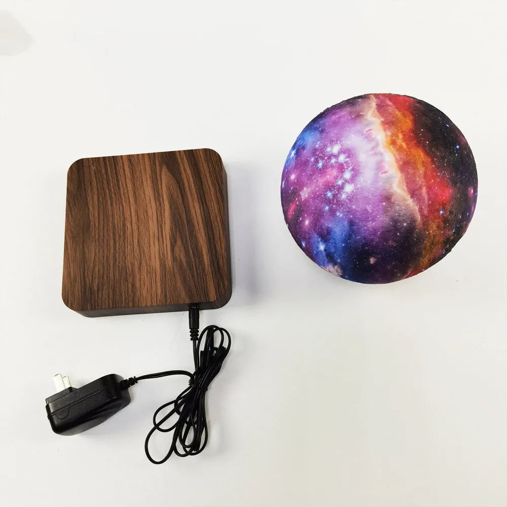Magnetic levitation galaxy moon lamp floating above walnut-coloured circular base with colourful star details