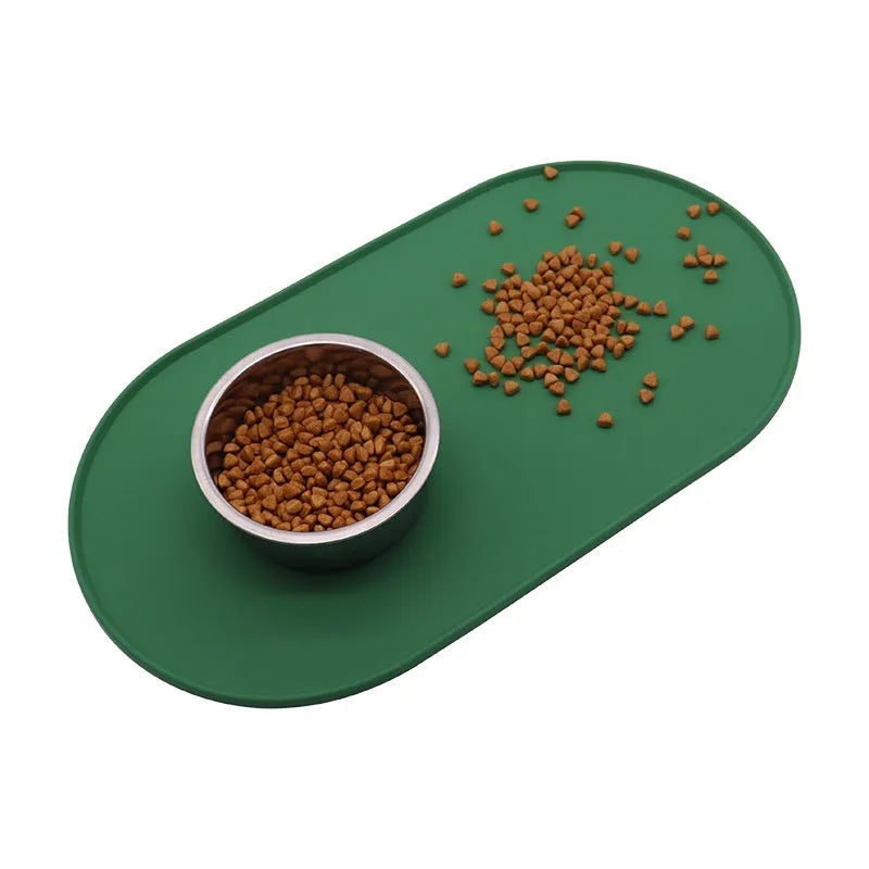 A green silicone placemat for cat food and water bowls on a wooden floor.