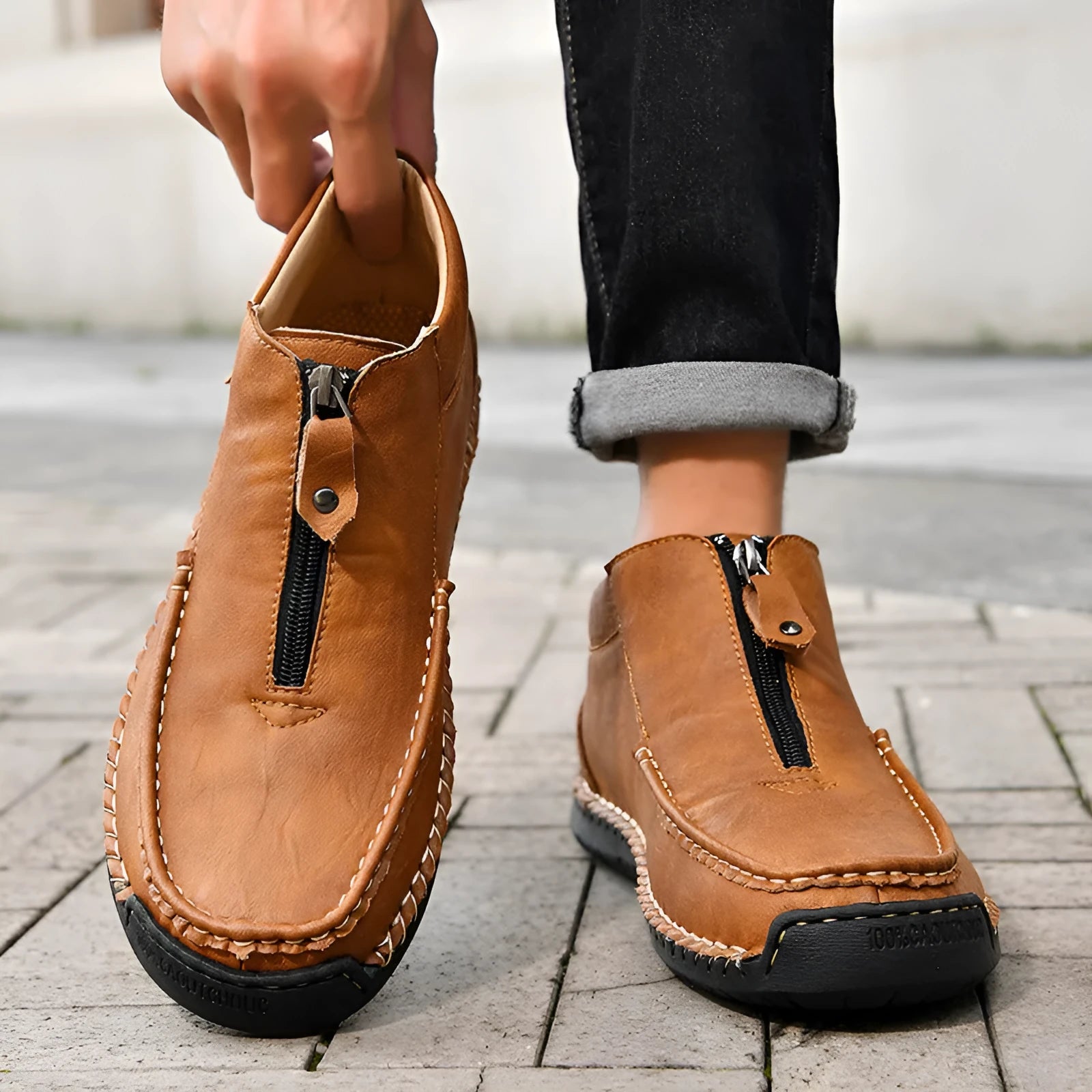 Men's black slip-on leather loafers with round toe and rubber sole, shown in a casual setting.