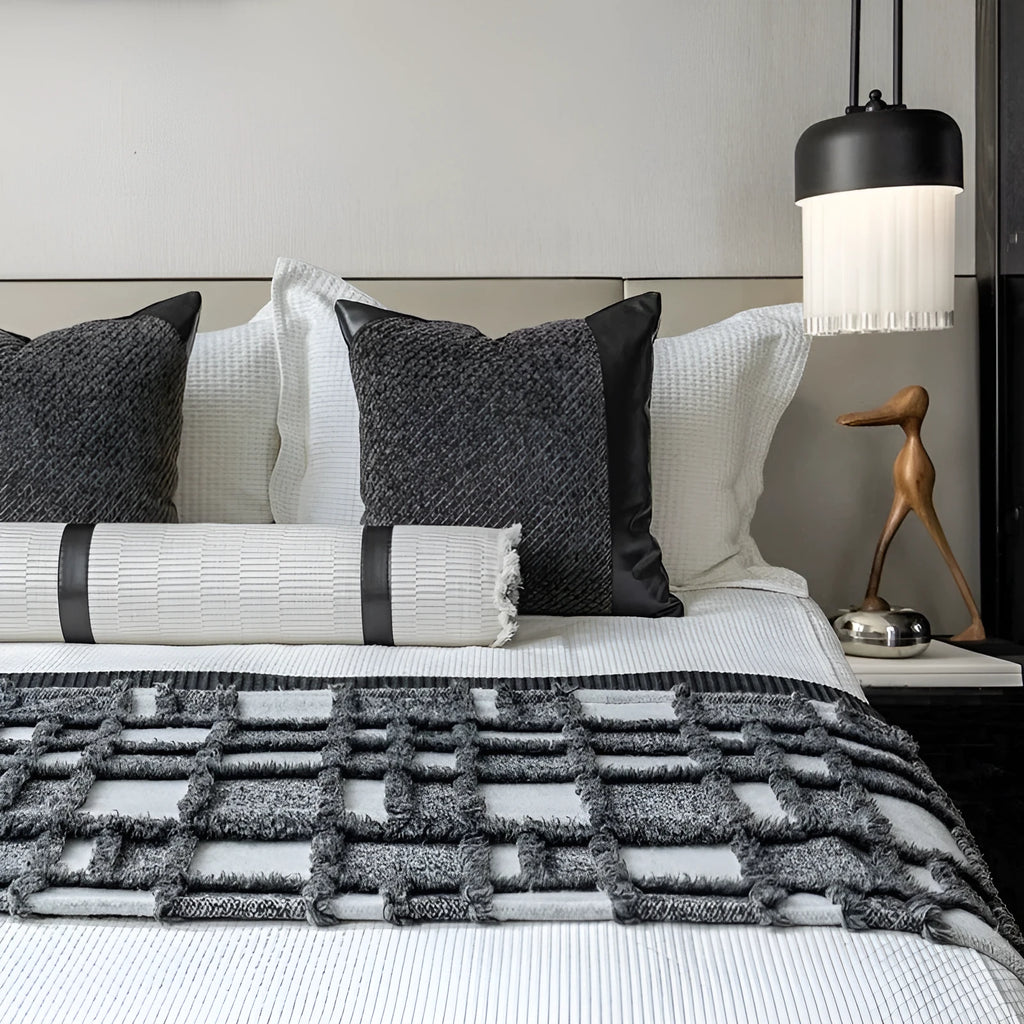 Modern minimalist bedding set with grey and white plaid blanket, pillowcase, and round pillow on bed