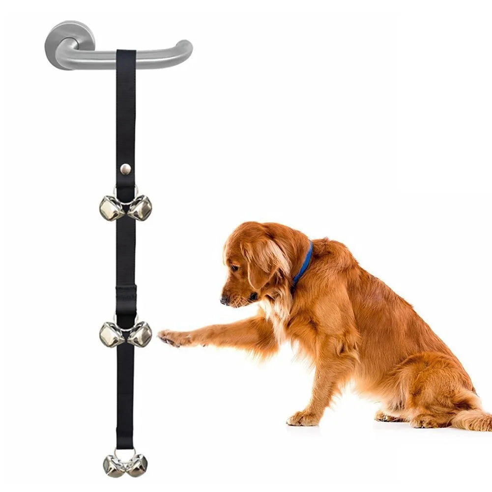Seven silver metal dog training bells on a black adjustable nylon strap hanging from a door handle.