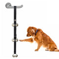 Seven silver metal dog training bells on a black adjustable nylon strap hanging from a door handle.