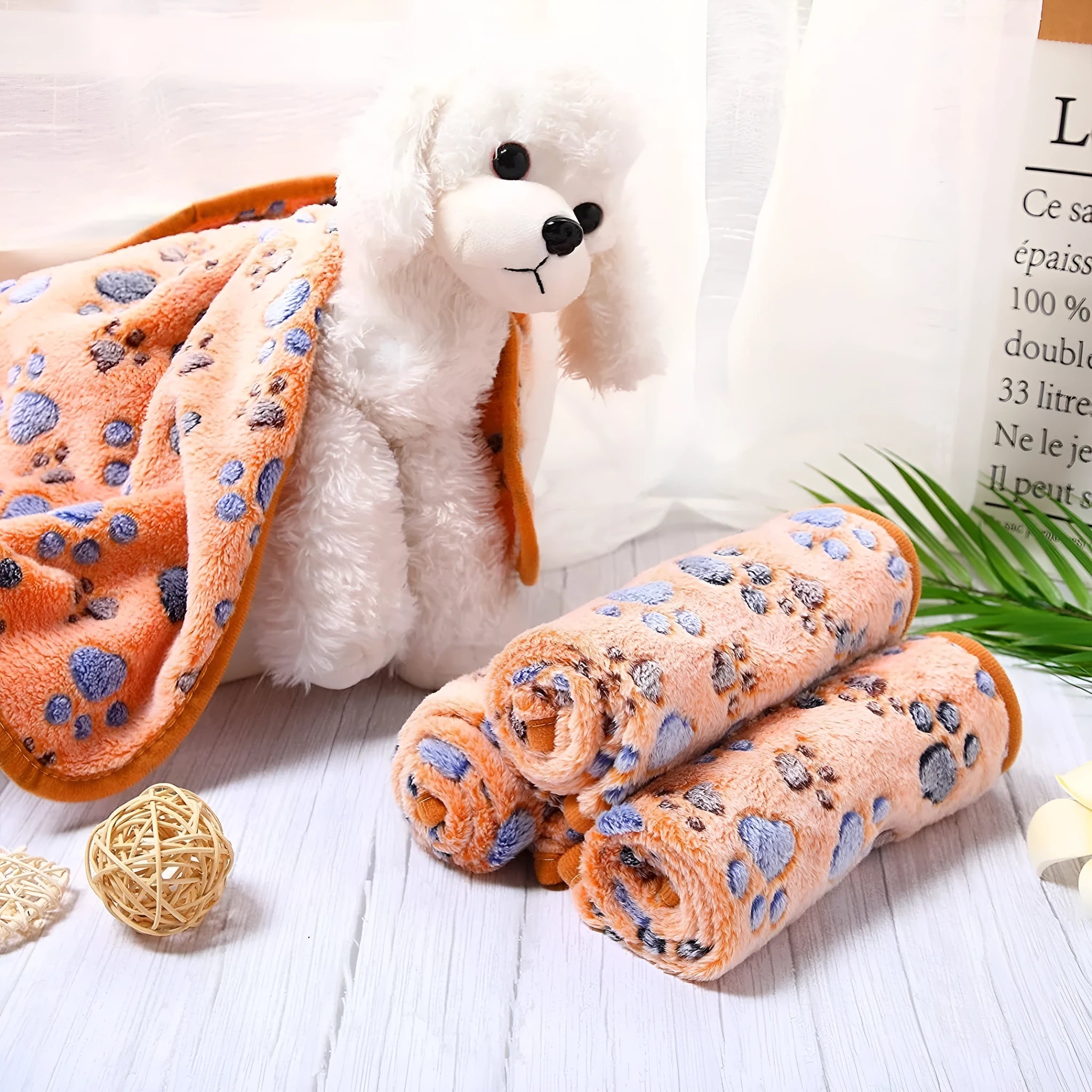 Coral fleece dog blanket with paw print pattern in beige, shown on a dog bed.
