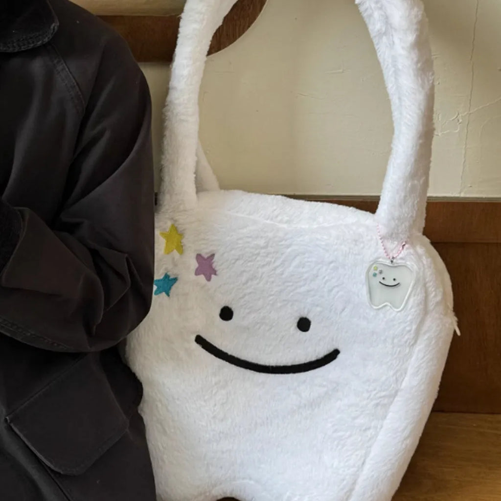 White plush tote bag with cute teeth pattern, showing crossbody strap and zipper closure.
