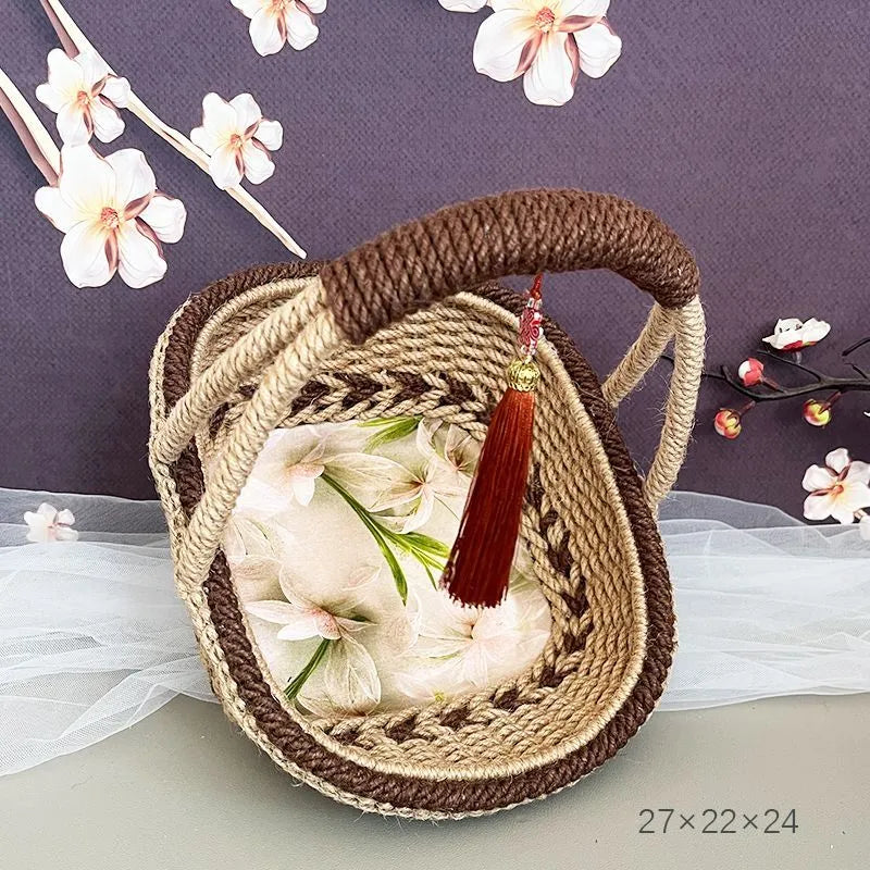 Coffee brown hand-woven straw basket with hemp rope handle, shown next to a small plant for scale.