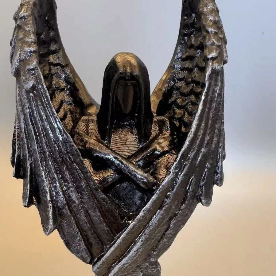 Small dark angel resin statue ornament on a table, showing detailed wings and robe.