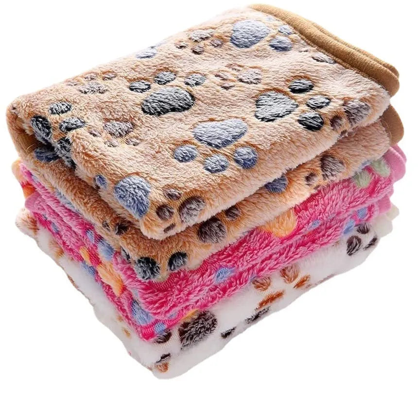 Coral fleece dog blanket with paw print pattern in beige, shown on a dog bed.