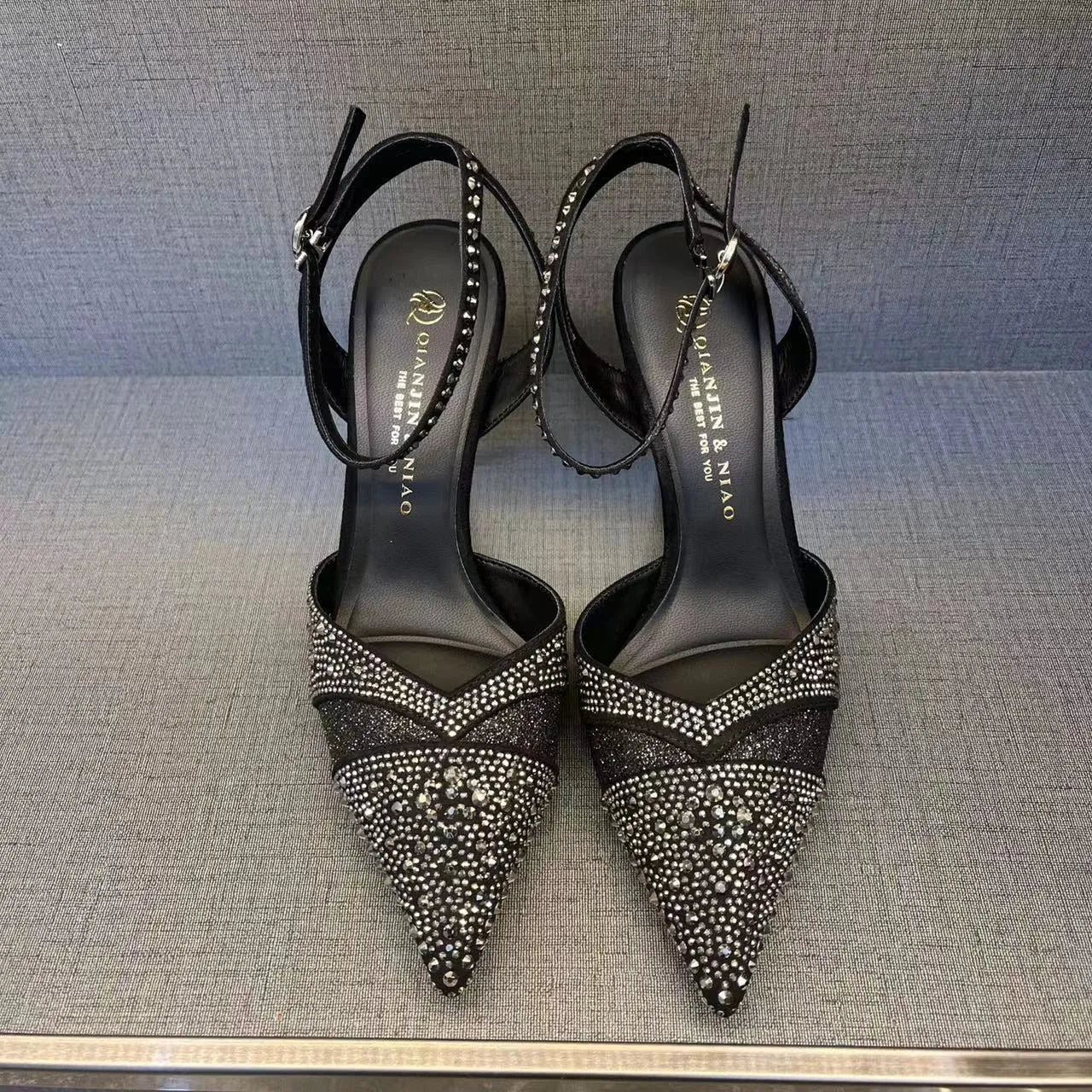 Women's black pointed toe high heels with a hollow stiletto heel and red sole, shown from the side.