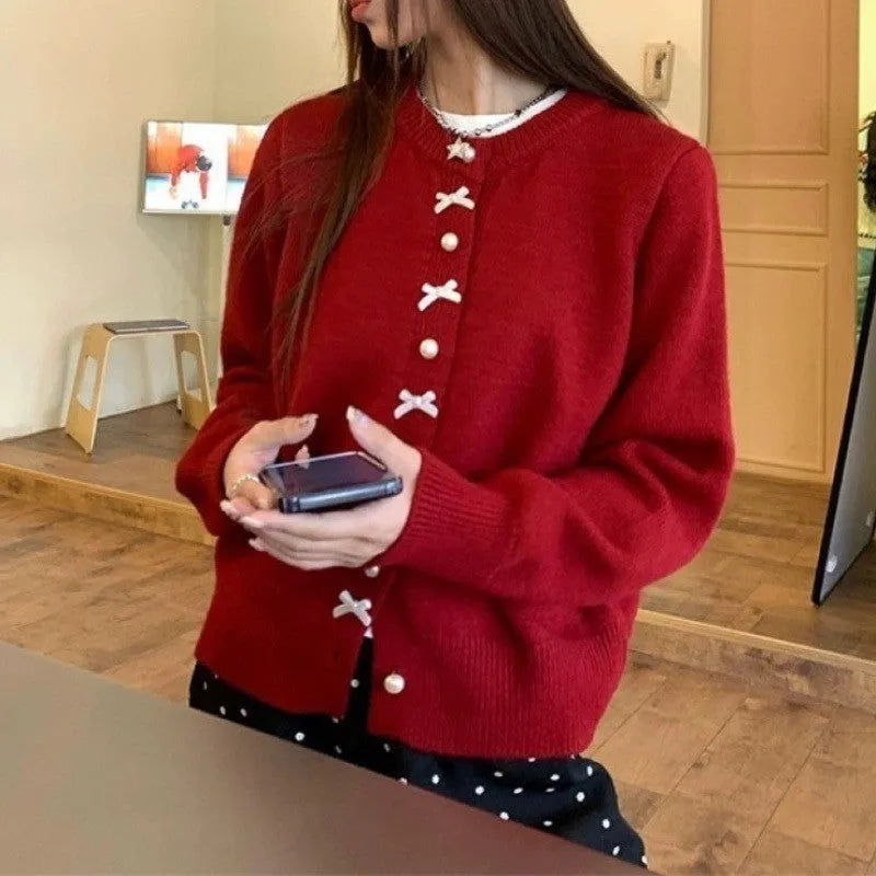 Women's light blue cashmere blend cardigan with white bow and pearl button detail on front.