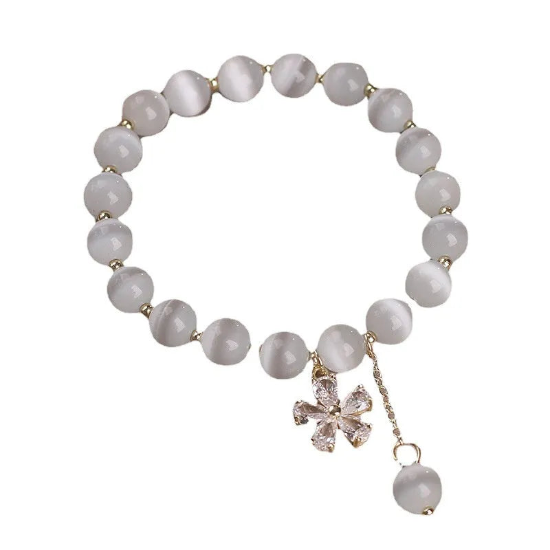 Single loop women's bracelet with white cat's eye stone, small flower tassel, and morganite safety buckle pendant.