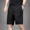 Man wearing loose fit grey polyester sports shorts with elastic waistband.