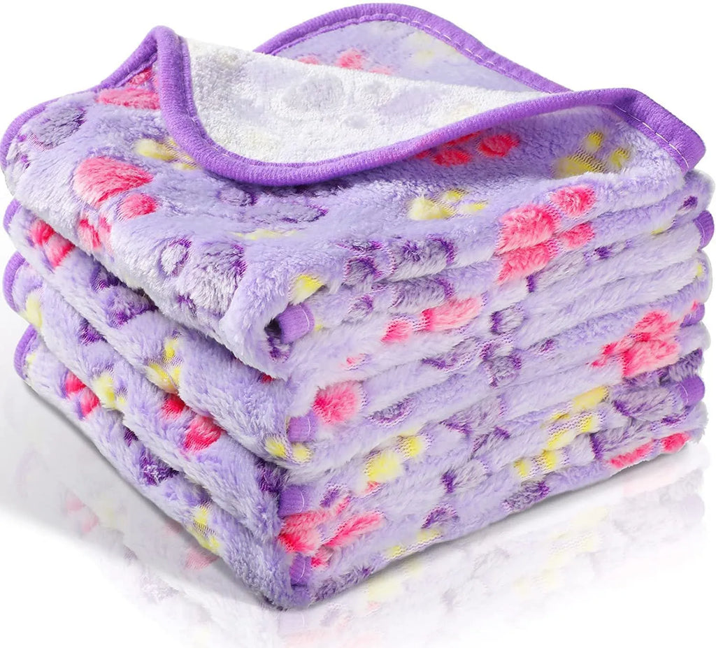 Coral fleece dog blanket with paw print pattern in beige, shown on a dog bed.