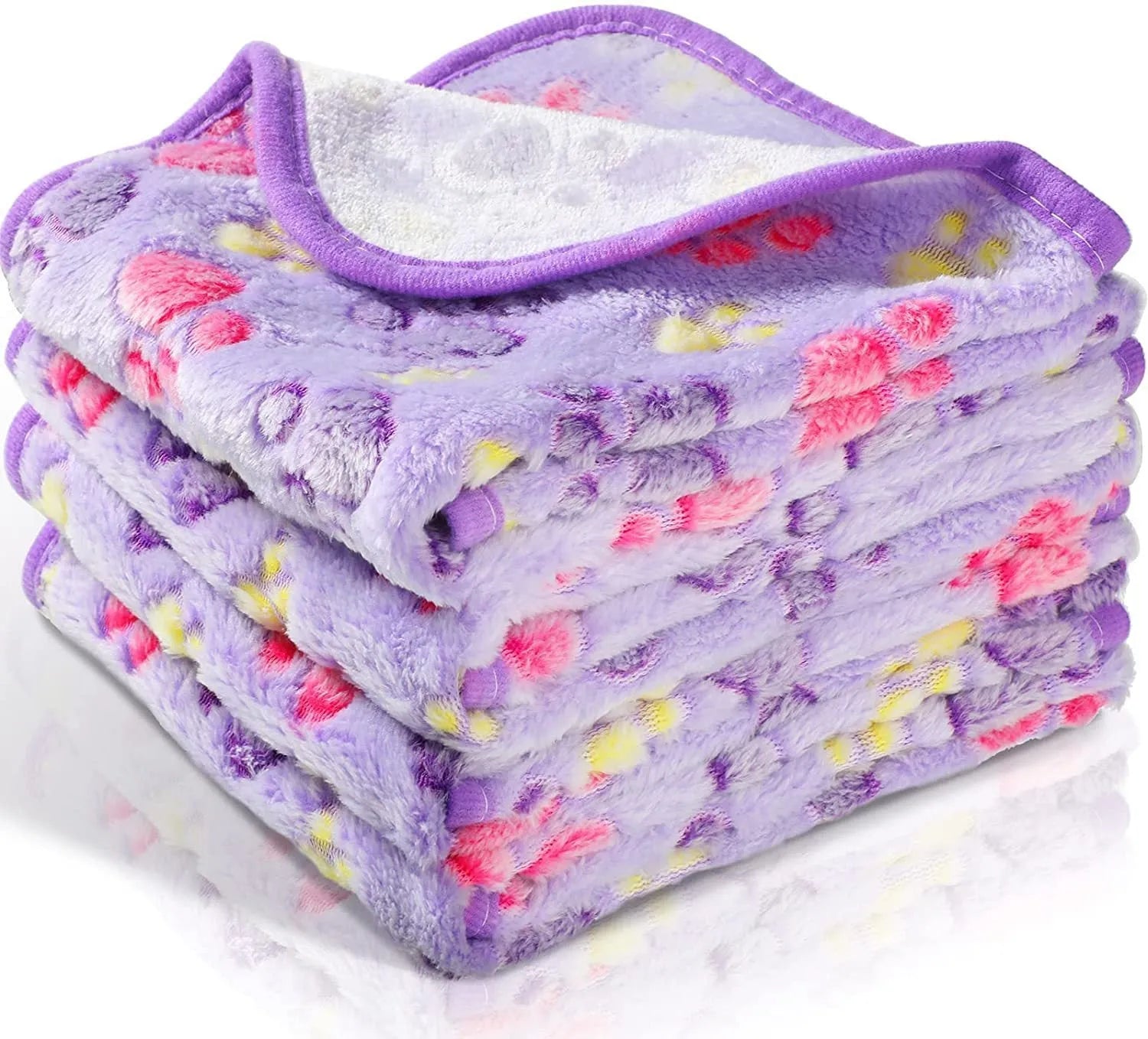 Coral fleece dog blanket with paw print pattern in beige, shown on a dog bed.