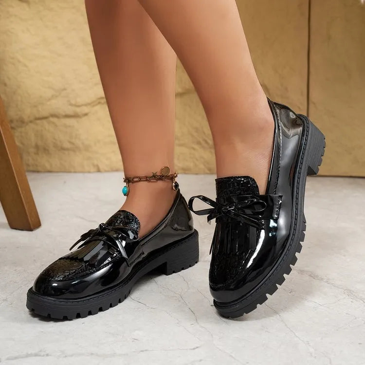 Women's black loafers with a decorative bow on the front.