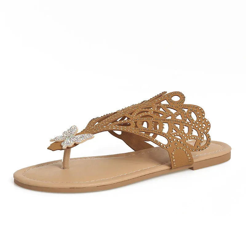 Women's black slip-on sandals with rhinestone decoration on the flip-toe, showing the flat heel and rubber sole.