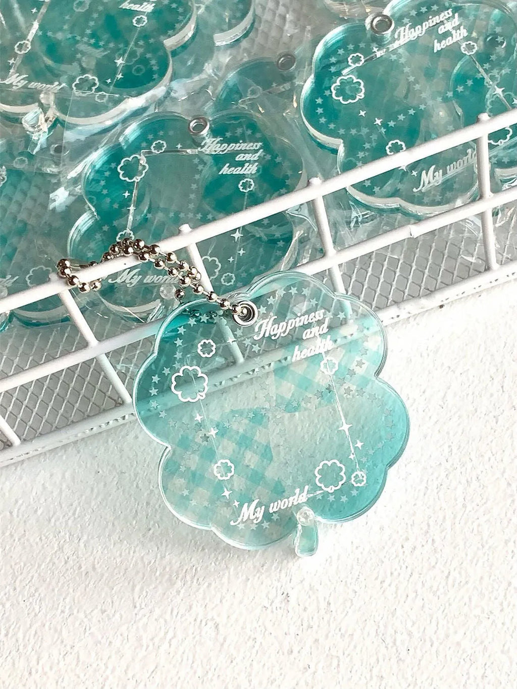 Acrylic four-leaf clover pendant keychain for phones in blue, green, and mint colour options.