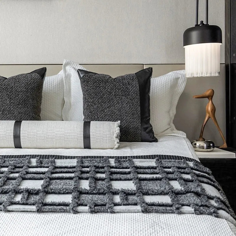 Modern minimalist bedding set with grey and white plaid blanket, pillowcase, and round pillow on bed
