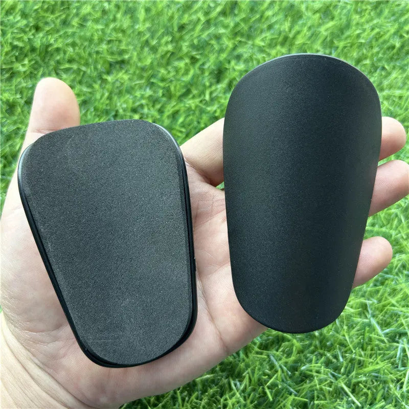 Extra small mini football shin guards measuring 8cm by 5cm in black and white plastic