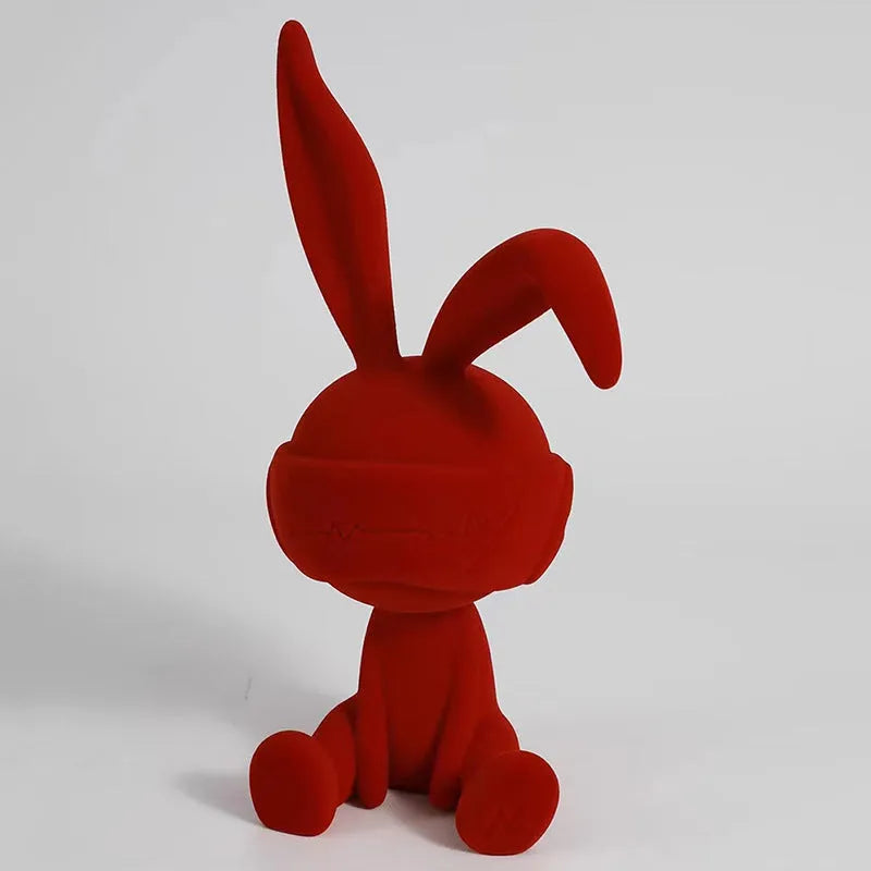 Small blue resin ornament of a rabbit wearing a blindfold on a wooden table.