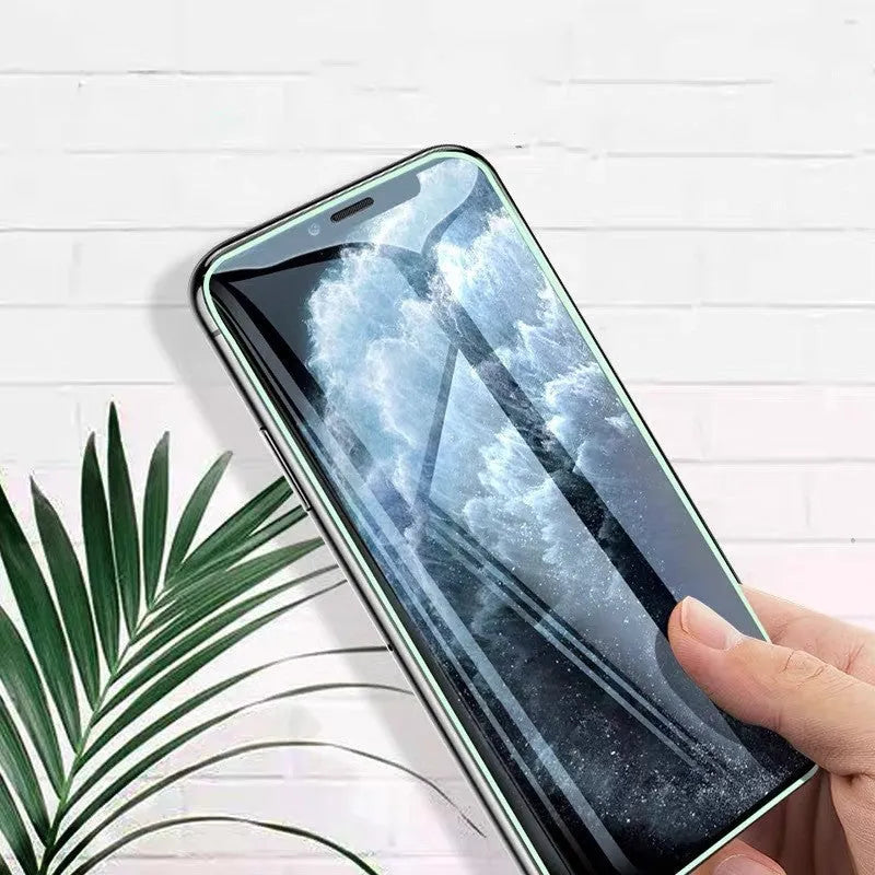 Luminous tempered glass screen protector for iPhone glowing softly in a dark setting.
