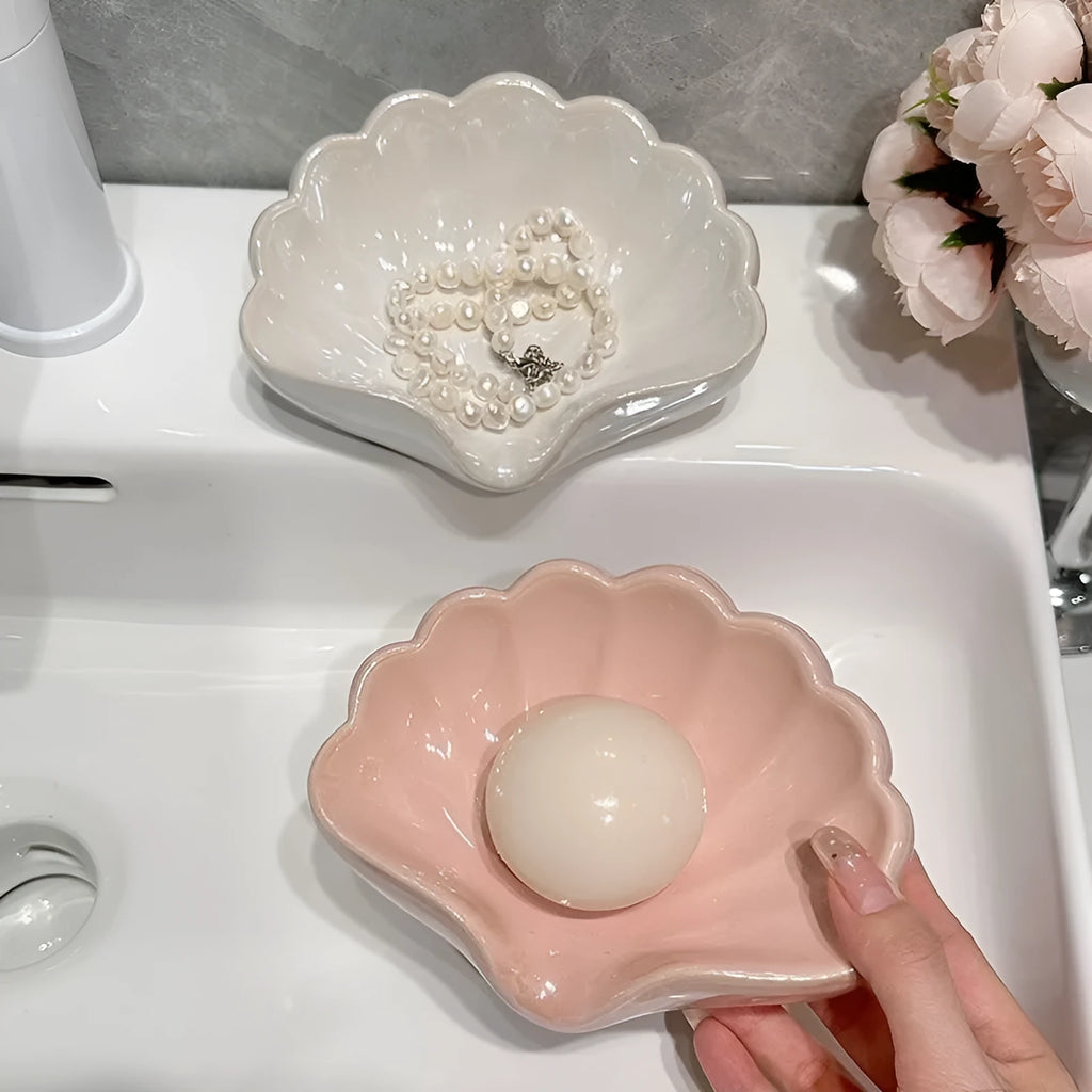 White shell-shaped plastic soap dish for bathroom use on a countertop.
