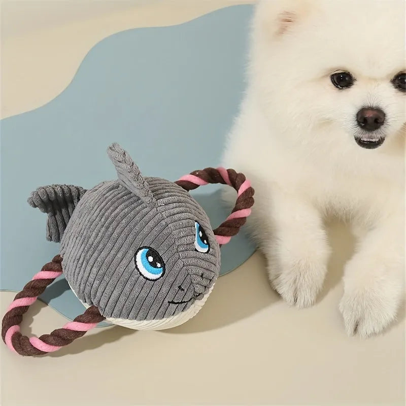 Grey turtle-shaped plush dog toy with four knotted rope legs on a wooden floor.