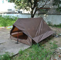 Brown A-line cabin tent pitched using hiking poles with aluminium ground nails and fluorescent wind ropes