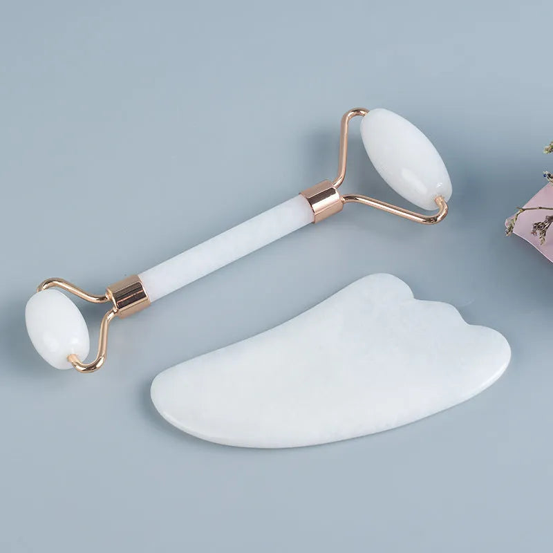 Natural white jade double-headed facial roller and gua sha board set on a plain background.