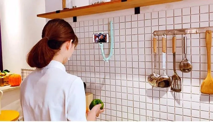Black flexible phone holder with suction cup mounted to wall showing 62cm adjustable arm holding mobile phone