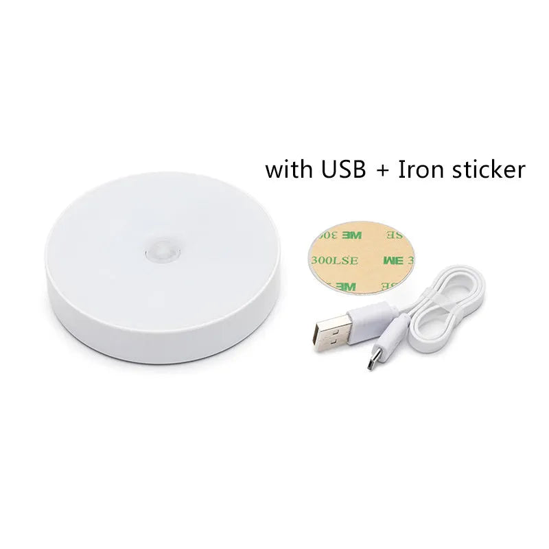 Small circular white motion sensing LED night light with USB charging cable and adhesive tape.