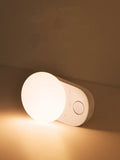 Baseus Sunshine Series white rechargeable motion sensor night light on a bedside table.