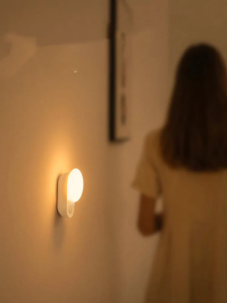 Baseus Sunshine Series white rechargeable motion sensor night light on a bedside table.