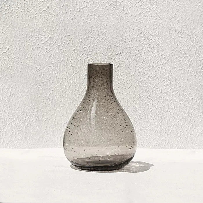 Grey geometric bubble-shaped stained glass vase on a wooden surface.