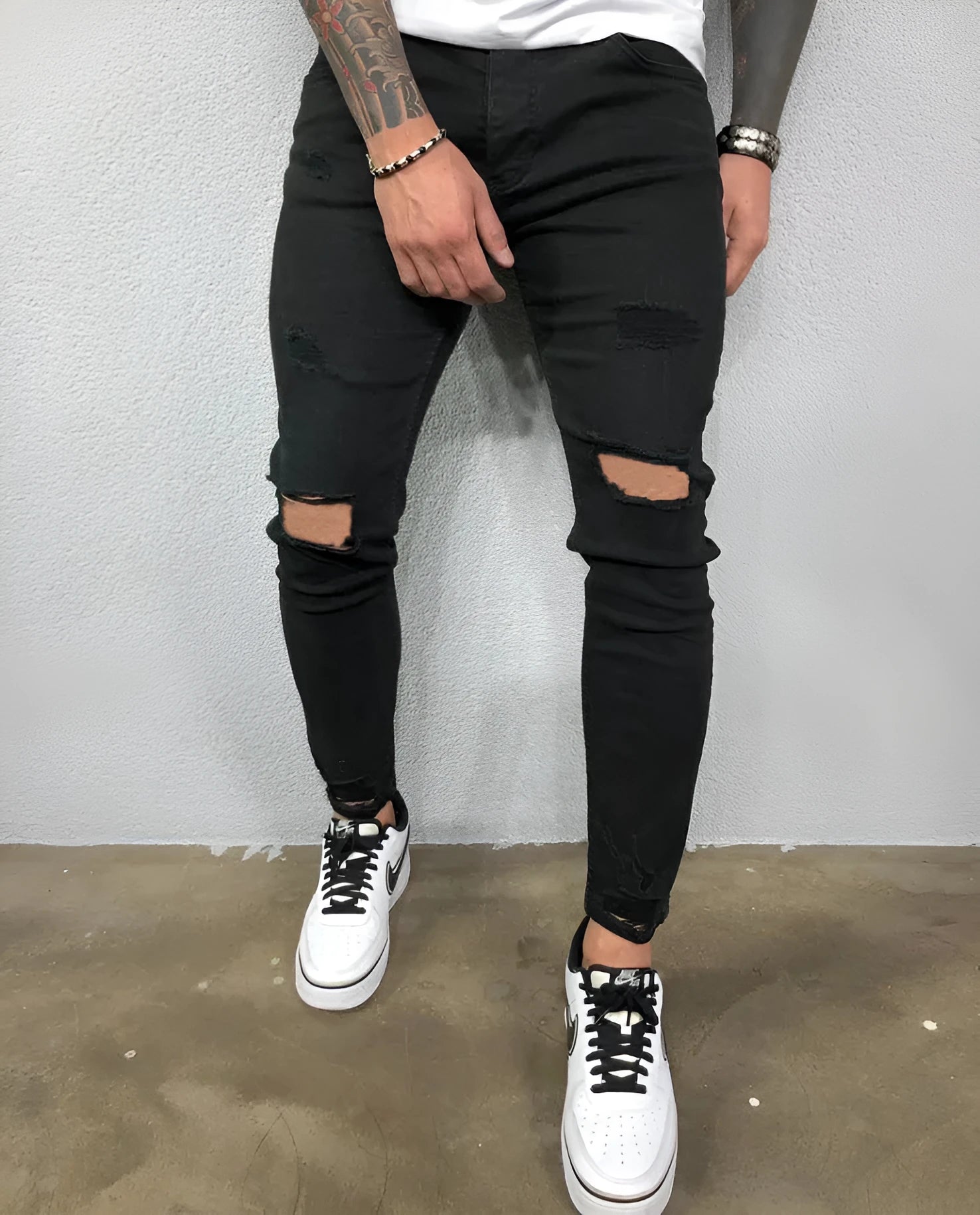 Men's skinny stretch denim jeans in black with ripped knee holes and tapered leg