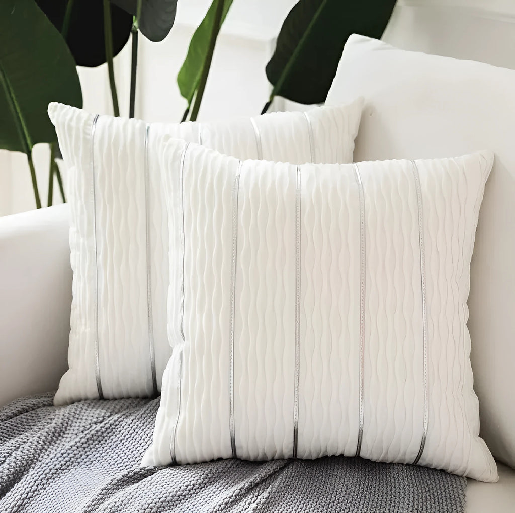 A square plush velvet pillow cover in a striped luxury style, shown in a selection of colours on a sofa.