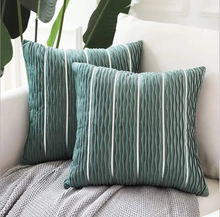 A square plush velvet pillow cover in a striped luxury style, shown in a selection of colours on a sofa.