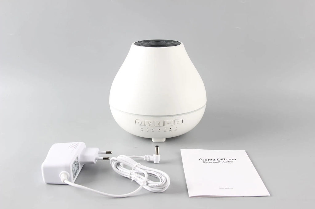 White round Bluetooth aroma diffuser humidifier with night light on a wooden surface.