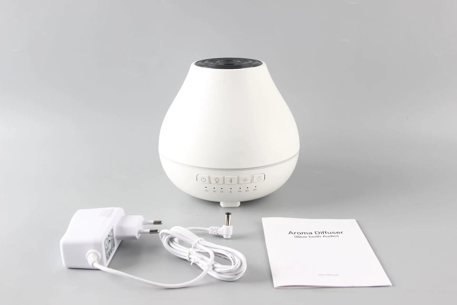 White round Bluetooth aroma diffuser humidifier with night light on a wooden surface.