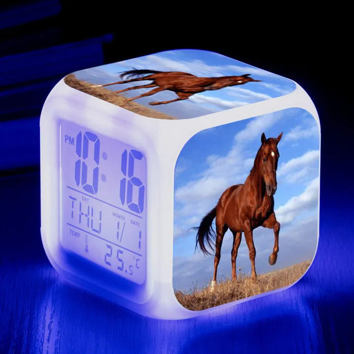Small square cartoon-style LED alarm clock showing digital time and temperature on a colourful display.