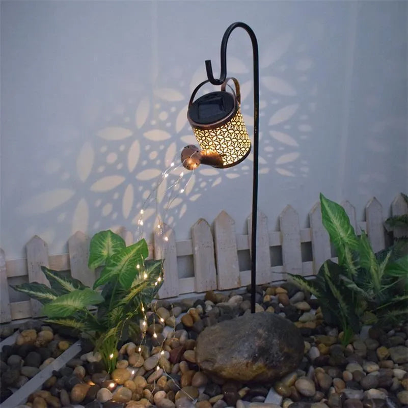 Solar watering can garden lamp with hollow-out iron shower body and 36 warm white LED lights on copper wire, installed in grass
