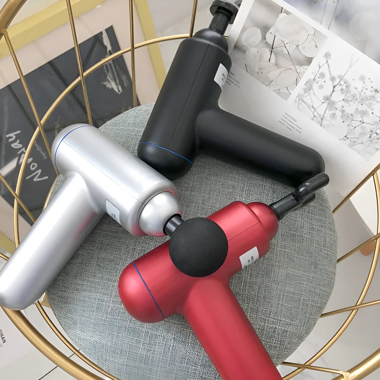 Black fascia gun massager with USB charging port shown alongside red and white colour variants