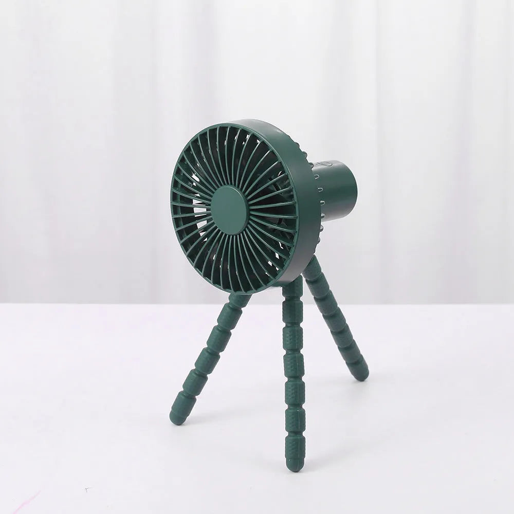 Small adjustable tripod desktop fan with bending head, shown in black on a desk.