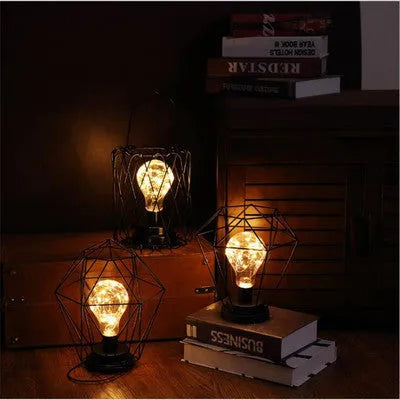 Hollow wrought iron wine bottle shaped table lamp with warm white LED light on a wooden desk