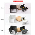 Small square aluminium wall lamp in black, mounted on a corridor wall, emitting a warm white light.