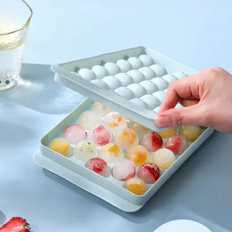 Blue silicone ice cube tray with lid showing round 33-grid design for homemade ice spheres