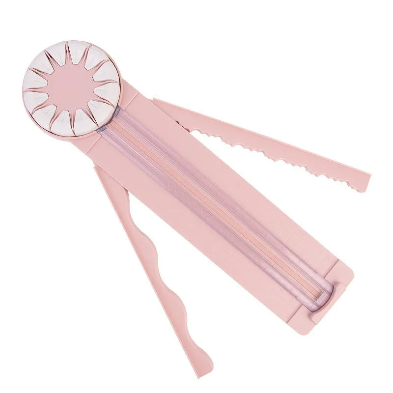 Pink and black 12-in-1 multifunctional plastic paper cutter with dotted guides on a cutting mat.